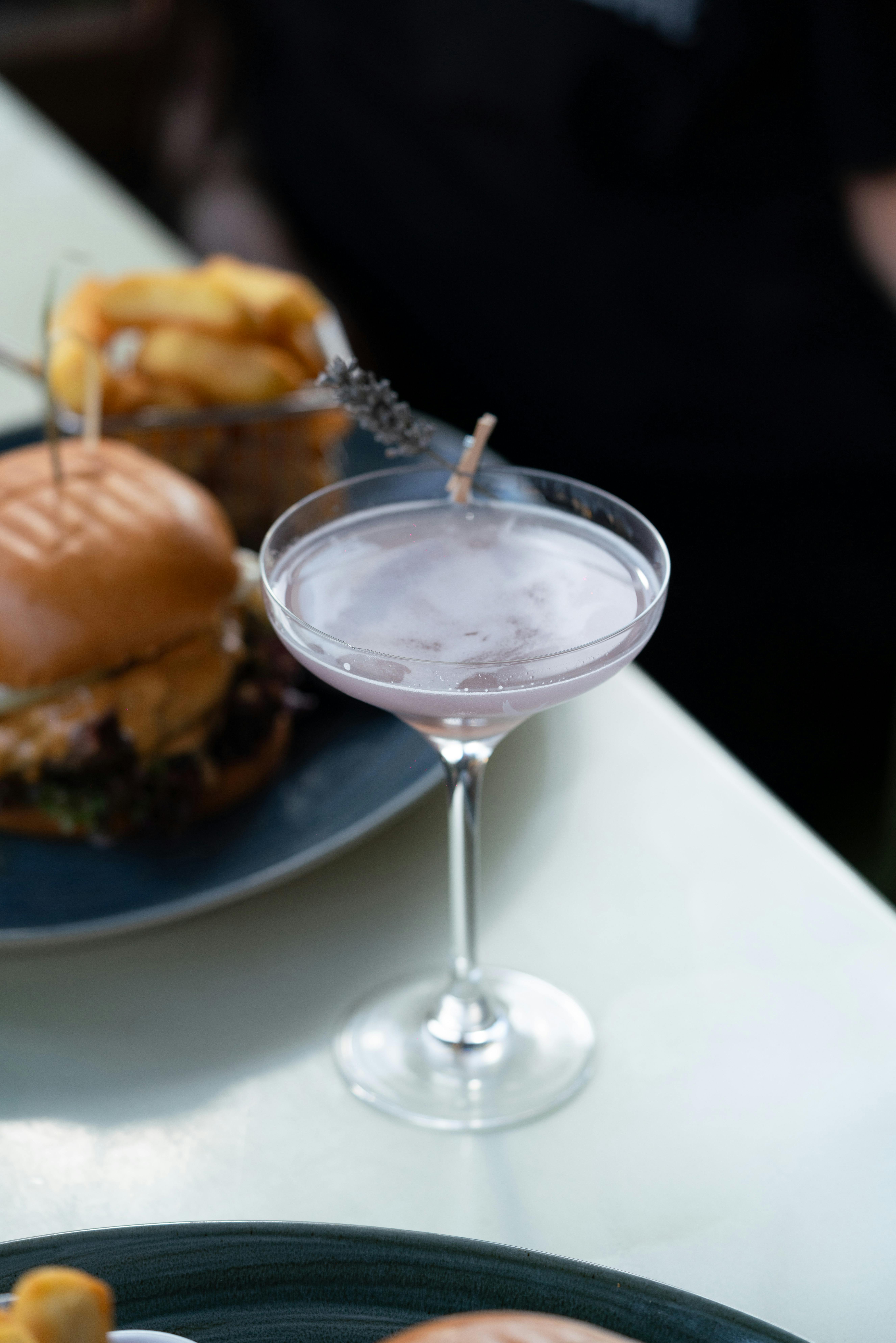 Cocktail with burger and fries in the background