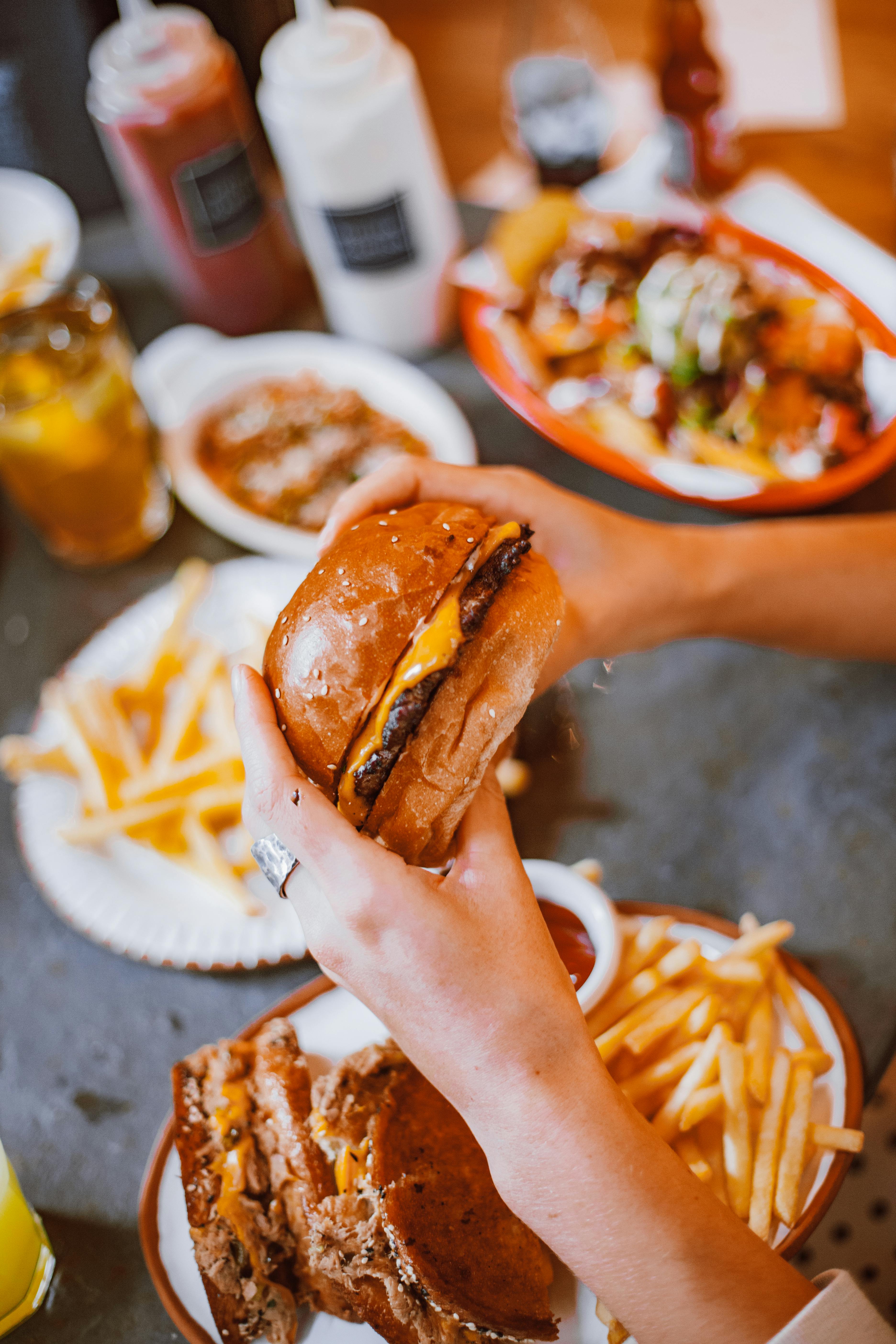 Person holding a cheeseburger over fries